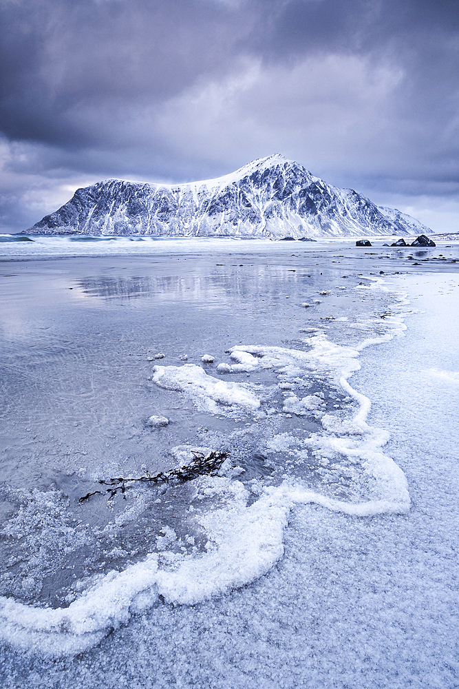 Frozen Wave Patterns on Skagsanden beach backed by Hustinden mountain winter, near Flakstad, Flakstadoya, Lofoten Islands, Nordland county, Norway, Scandanavia, Europe