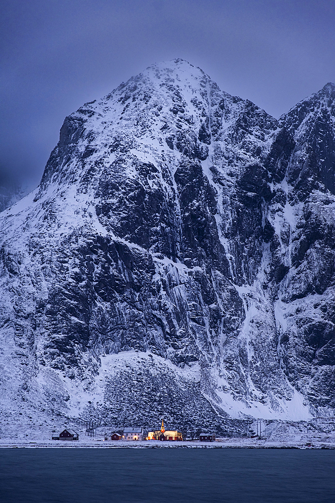 Flakstad Kirke (Flakstad Church) and Flakstadtind Mountain across Flakstadpollen Fjord at night in winter, Flakstad Municipality, Nordland County, Lofoten Islands, Norway, Scandinavia, Europe