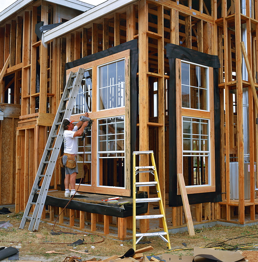 Man using a drill in the construction of a wood framed house in California, United States of America, North America