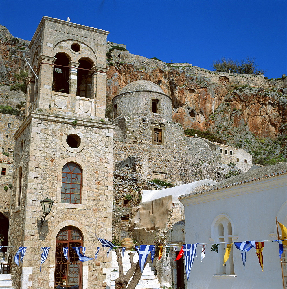 Greek flags and bunting for Independence Day, in front of the bell tower and church at Monemvasia, the Gibraltar of Greece, Greece, Europe