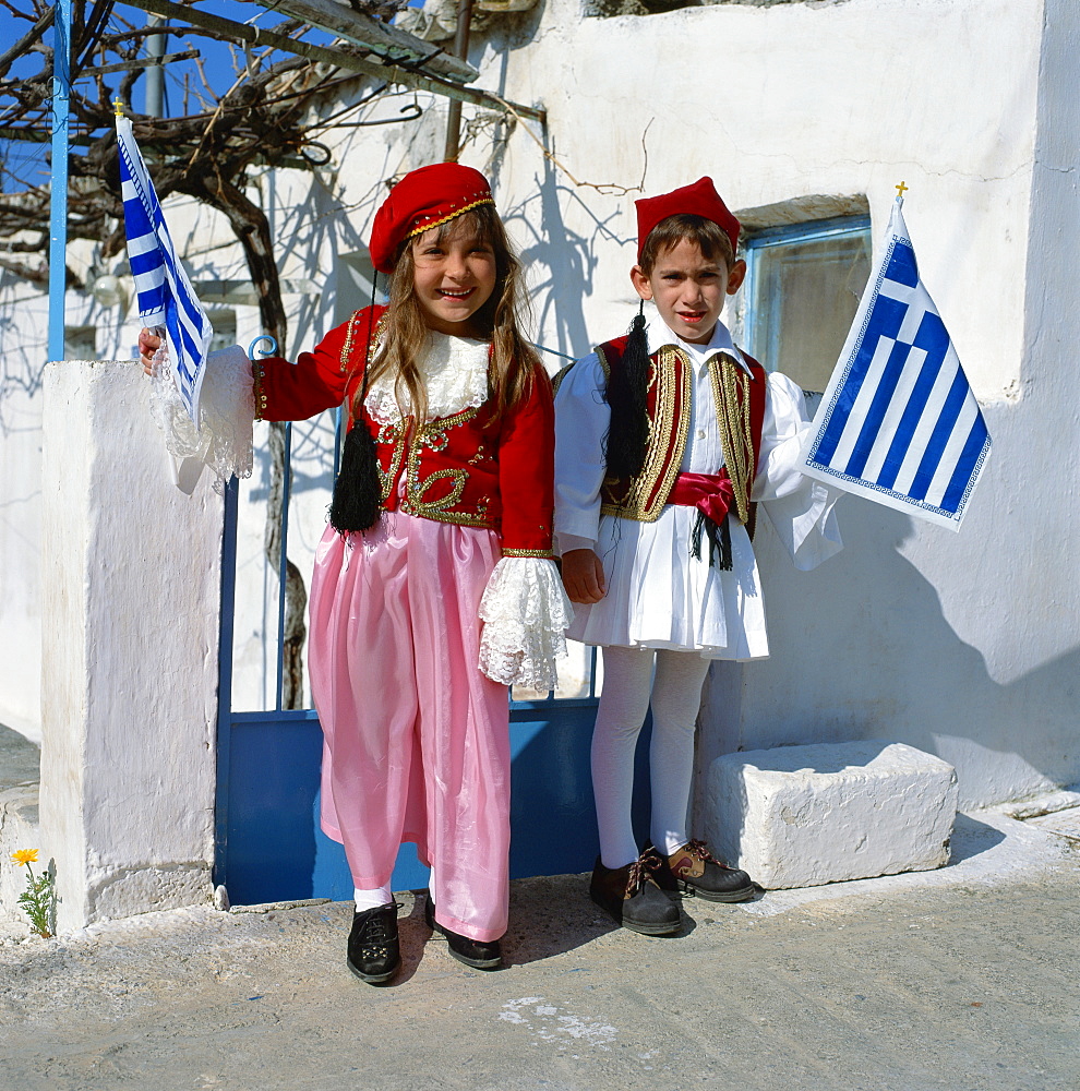 Portrait of two children in national dress carrying flags, celebrating Independence Day, in Greece, Europe