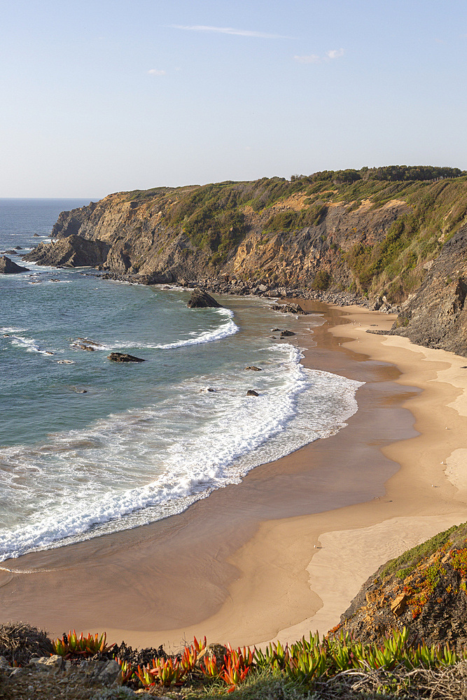 Secluded sandy beach in bay between rocky headlands at Parque Natural do Sudoeste Alentejano e Costa Vicentina, view on the Ruta Vicentina, long distance walking trail, at Praia dos Machados, Carvalhal, Alentejo Littoral, Portugal, Europe