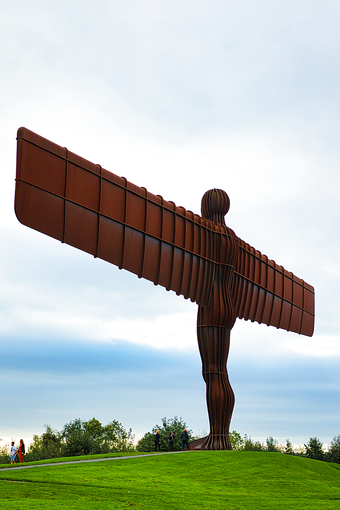 Large angel sculpture with outstretched wings against a cloudy sky, symbolizing hope and freedom.