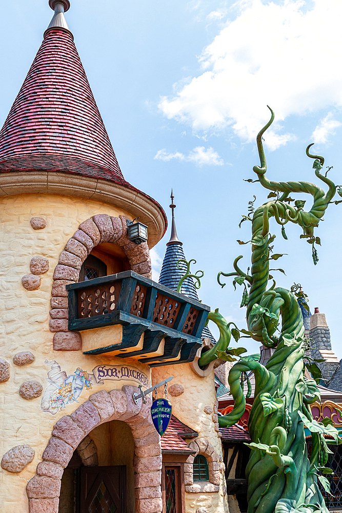 Whimsical building with a red-roofed tower and a decorative green beanstalk under a blue sky at Disneyland Paris.