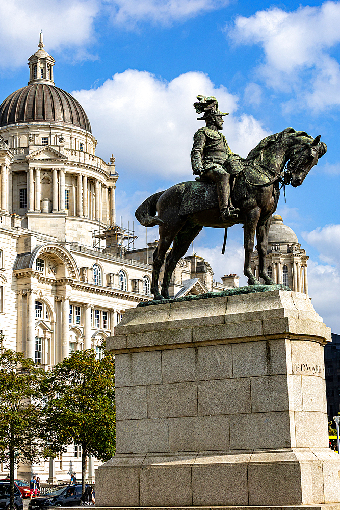 An equestrian statue stands in front of a classical building with a dome and ornate columns under a blue sky with clouds in Liverpool, UK.