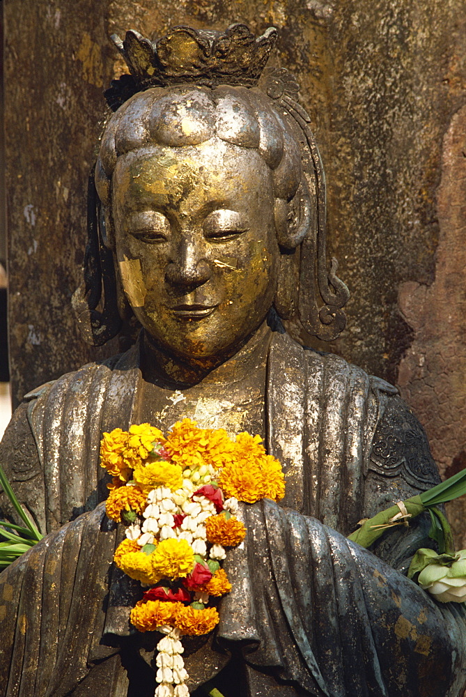 Detail of statue with offering of marigold flowers in the Emerald Buddha Temple in Bangkok, Thailand, Southeast Asia, Asia