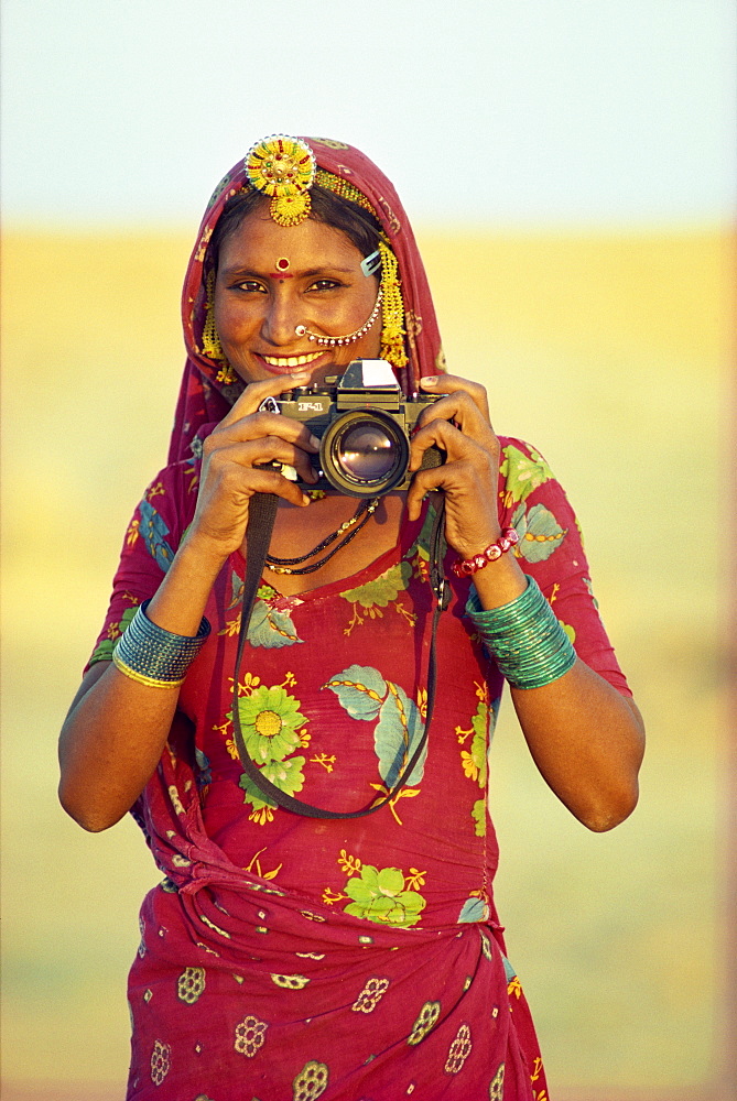 Portrait of indigenous woman holding tourist's camera, Thar Desert, near Jaisalmer, Rajasthan, India, Asia