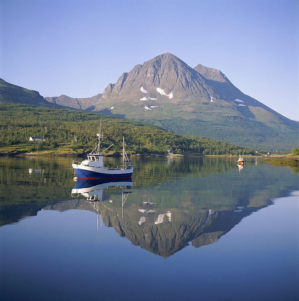 Boat and mountains reflected in tranquil water, near Tromso, north Norway, Norway, Scandinavia, Europe