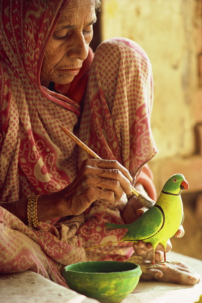 A woman paints a clay toy parrot, northern India, India, Asia