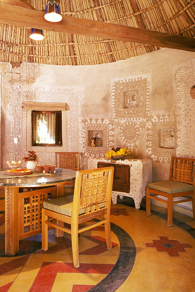 Raised mud reliefs inlaid with mirror on the walls of dining area in modern home in traditional tribal Rabari round mud hut, Bunga style, near Ahmedabad, Gujarat state, India, Asia