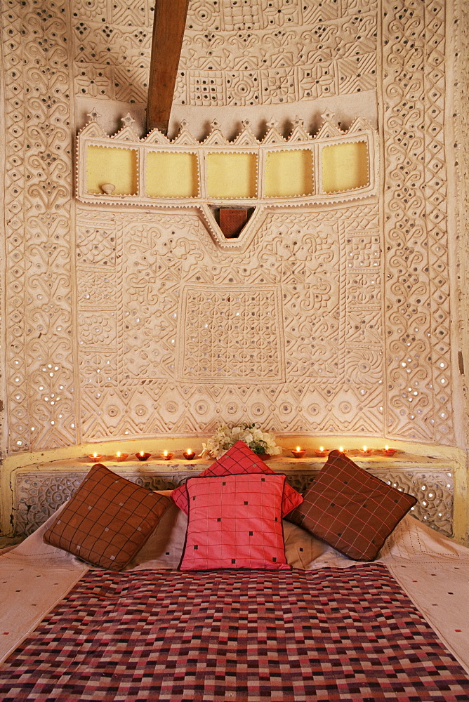 Raised mud reliefs inlaid with mirror on the walls of bedroom in modern home in traditional tribal Rabari round mud hut, Bunga style, near Ahmedabad, Gujarat state, India, Asia