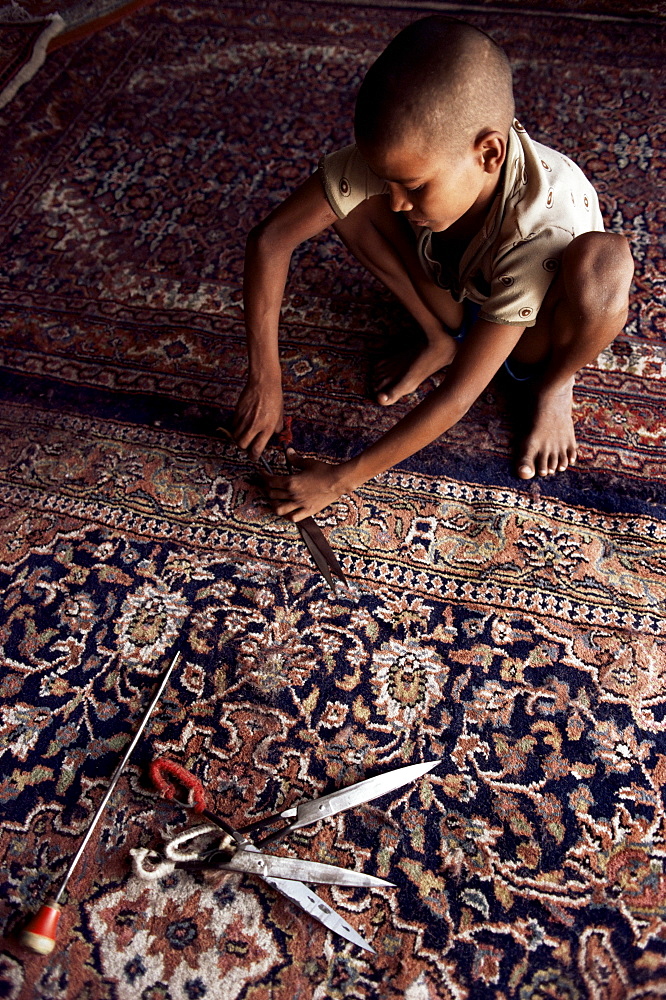 Child clipping and finishing carpet, Varanasi (Benares), Uttar Pradesh state, India, Asia