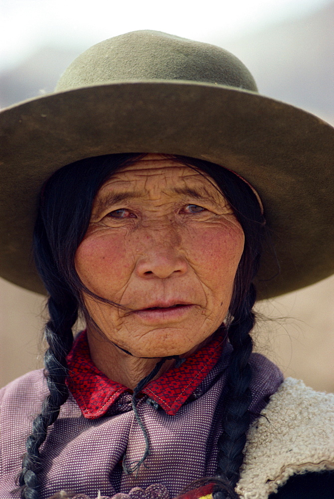 Portrait of a Tibetan woman with plaits and hat on the Qinghai Plateau, China, Asia