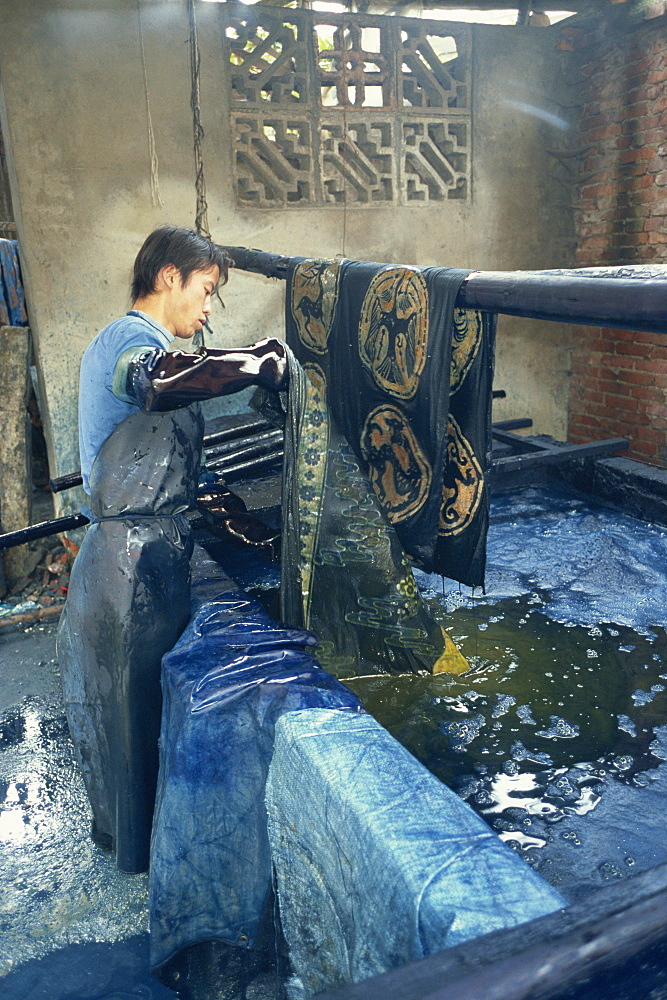 Dipping batik in an indigo vat, Guizhou, China, Asia