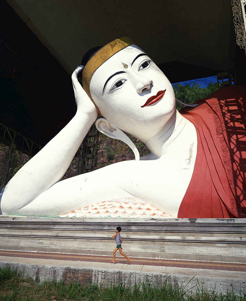 Young boy running in front of reclining Shwe Tha Lyaung Buddha, Mergui (Myeik), Myanmar (Burma), Asia