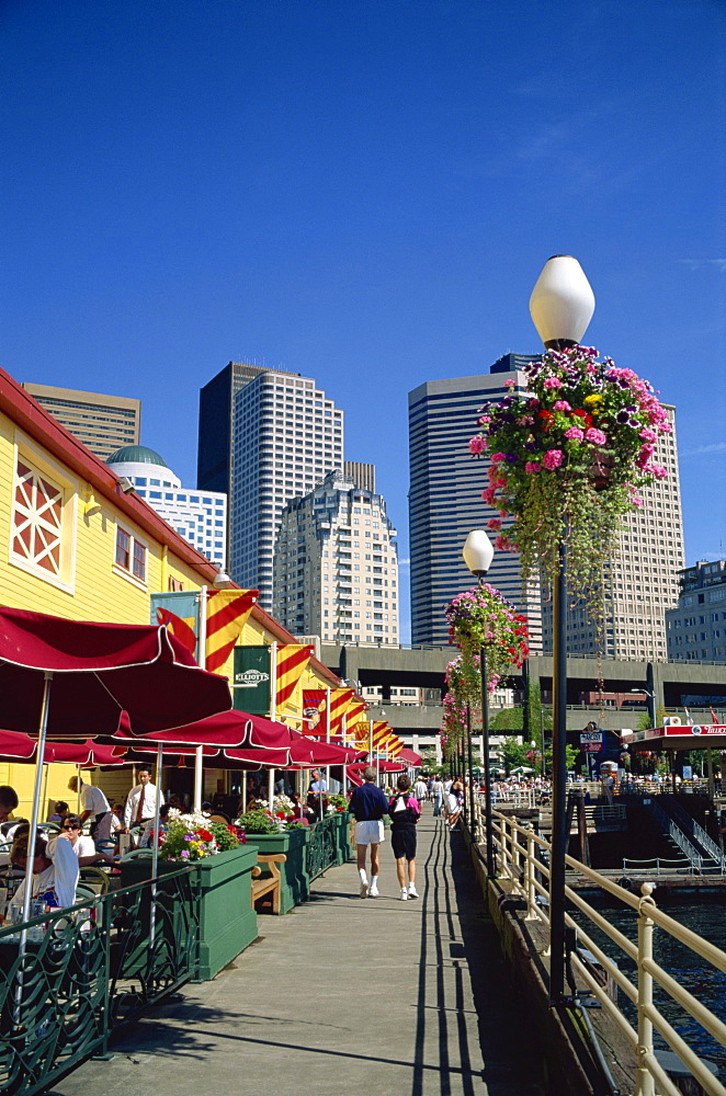 Cafes on Pier 56 on the waterfront with tower blocks of the city in the background, in Seattle, Washington State, United States of America, North America