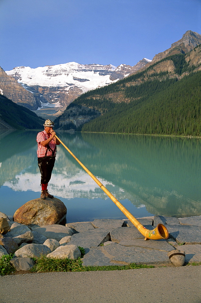 Man with an alpenhorn beside Lake Louise in the Banff National Park, Alberta, Canada, North America