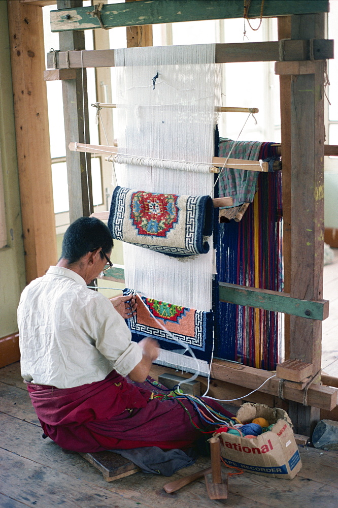 Man working at a loom weaving a carpet in Bhutan, Asia