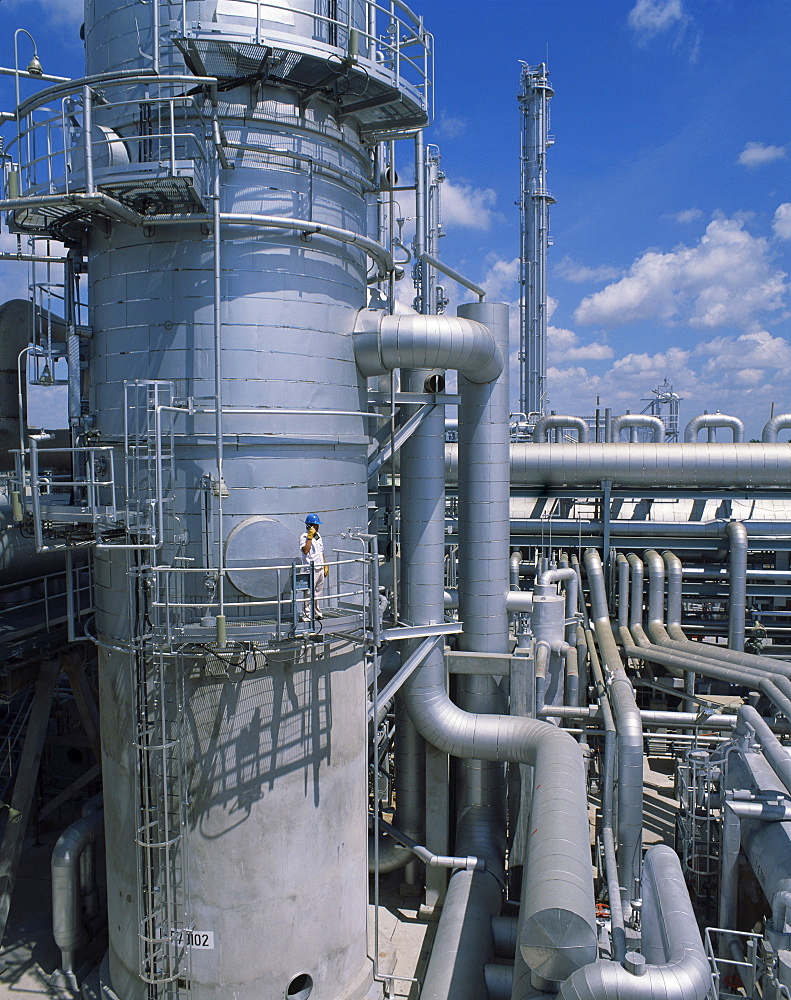 A worker wearing hard hat and using a mobile phone at the natural gas plant at Mabta Pud in Thailand, Southeast Asia, Asia