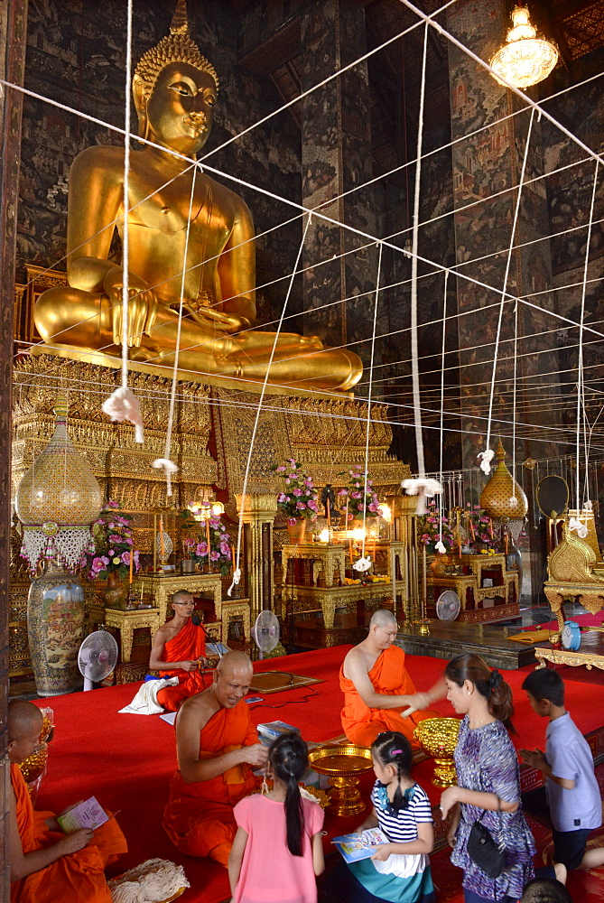 Monk blessing people in the main Viharn of Wat Suthat Bangkok, Thailand, Southeast Asia, Asia