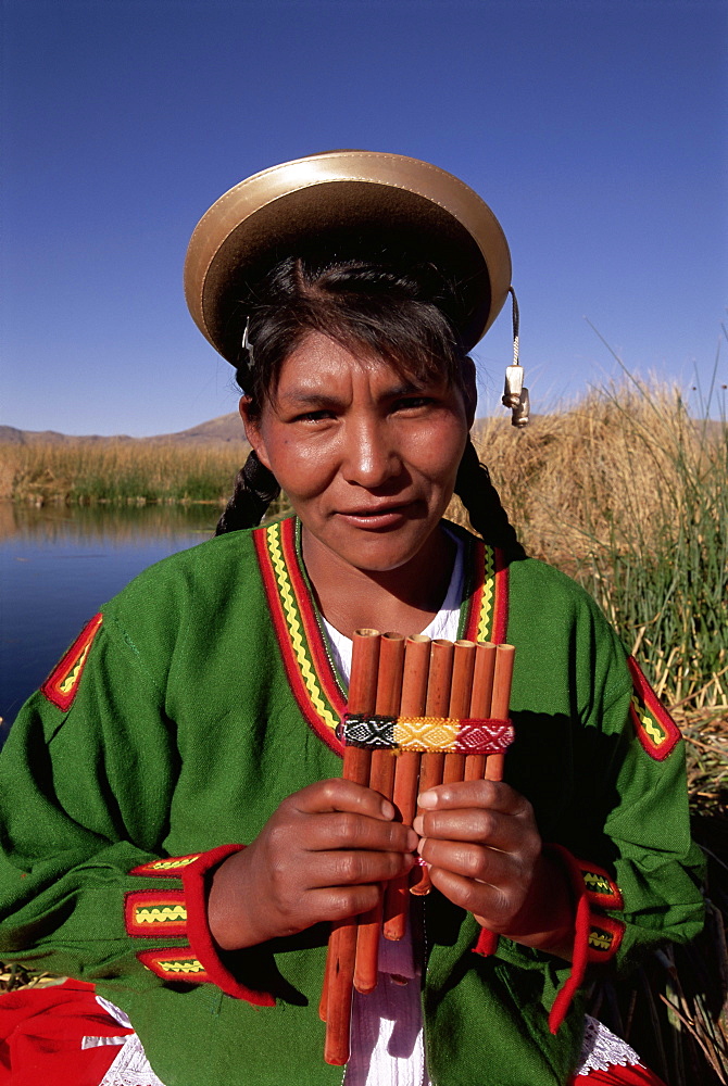 Head and shoulders portrait of a Uros Indian woman holding pipes, on floating reed island, Islas Flotantes, Lake Titicaca, Peru, South America