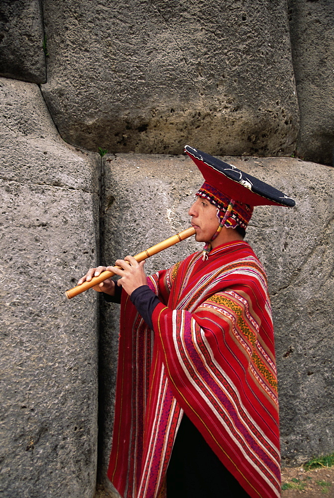 Portrait of a Peruvian man playing a flute, Inca ruins of Sacsayhuaman, Cuzco, Peru, South America