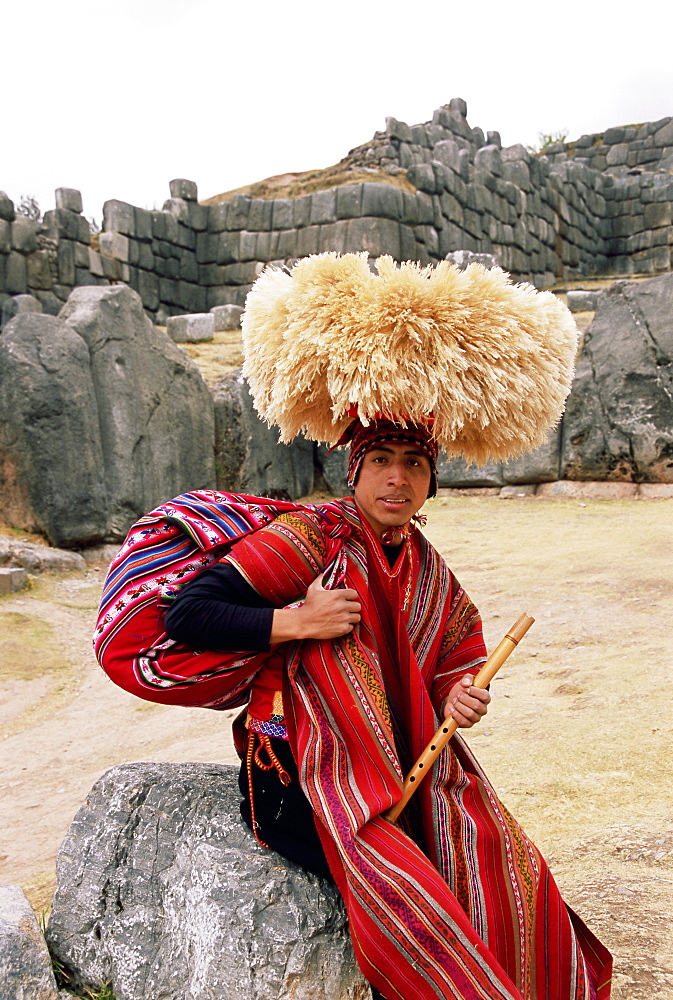 Portrait of a young Peruvian man in traditional dress, with a flute, Inca ruins of Sacsayhuaman, Cuzco, Peru, South America