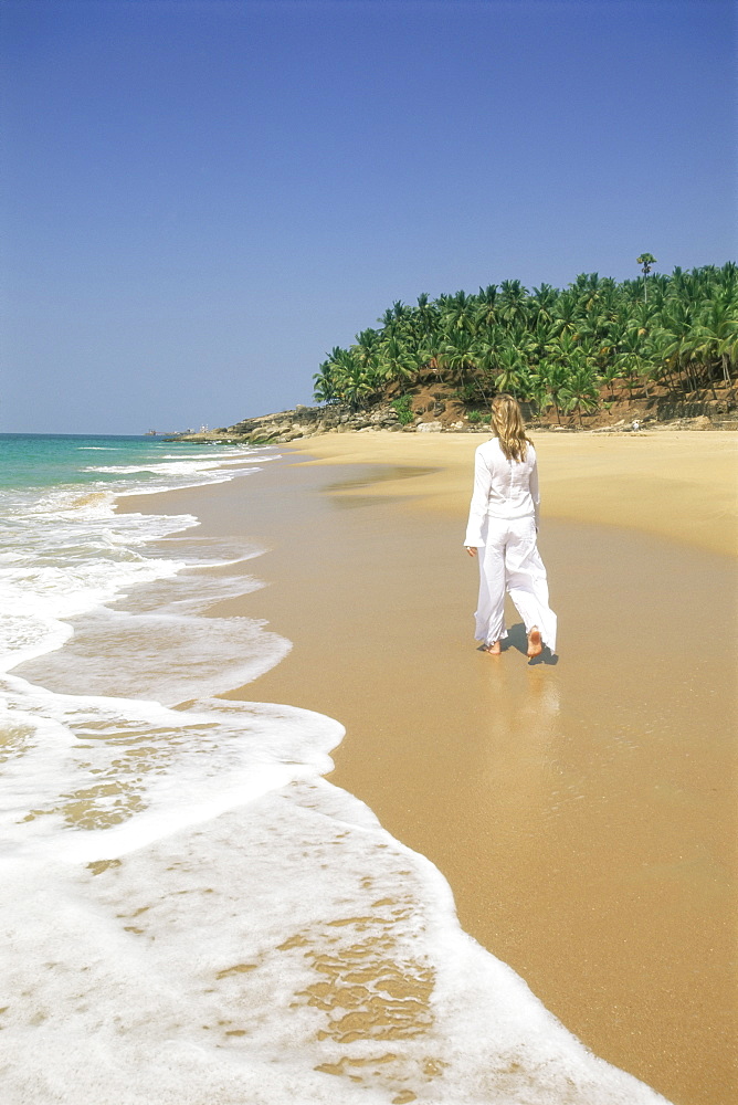 Woman tourist walking along the beach, Kovalam, Kerala state, India, Asia