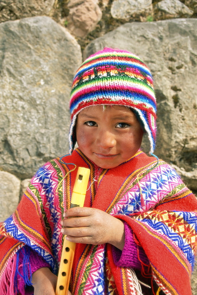 Portrait of a Peruvian boy in a knitted hat, playing the flute, near Cuzco, Peru, South America