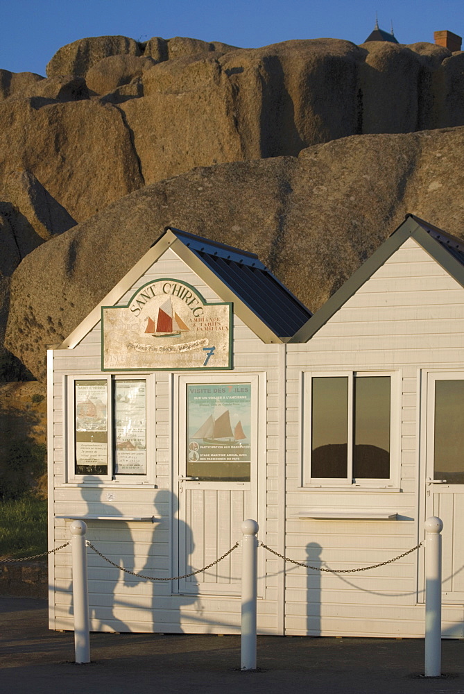 Shadow of couple walking past beach huts in front of granite boulders, Tregastel, Cote de Granit Rose, Cotes d'Armor, Brittany, France, Europe