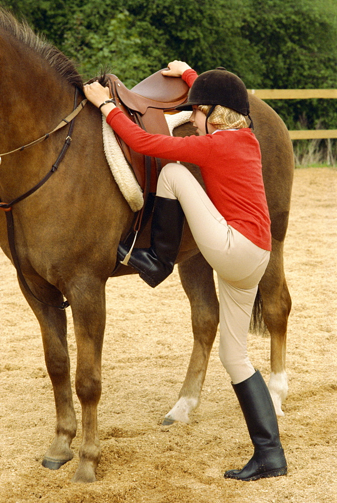 Teenage girl mounting horse, England, United Kingdom, Europe