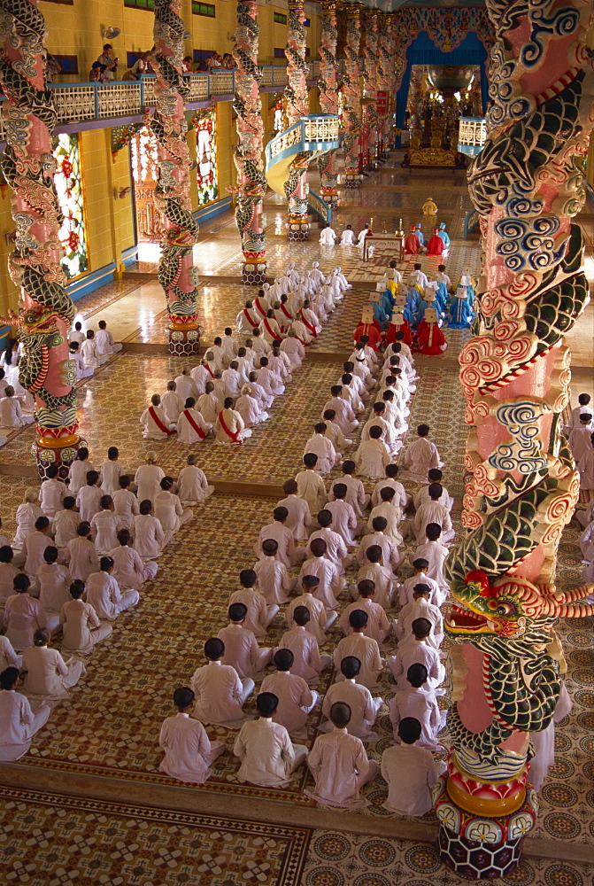 Rows of monks at prayer inside a temple of the Caodai religious sect, at Tay Ninh, Vietnam, Indochina, Southeast Asia, Asia