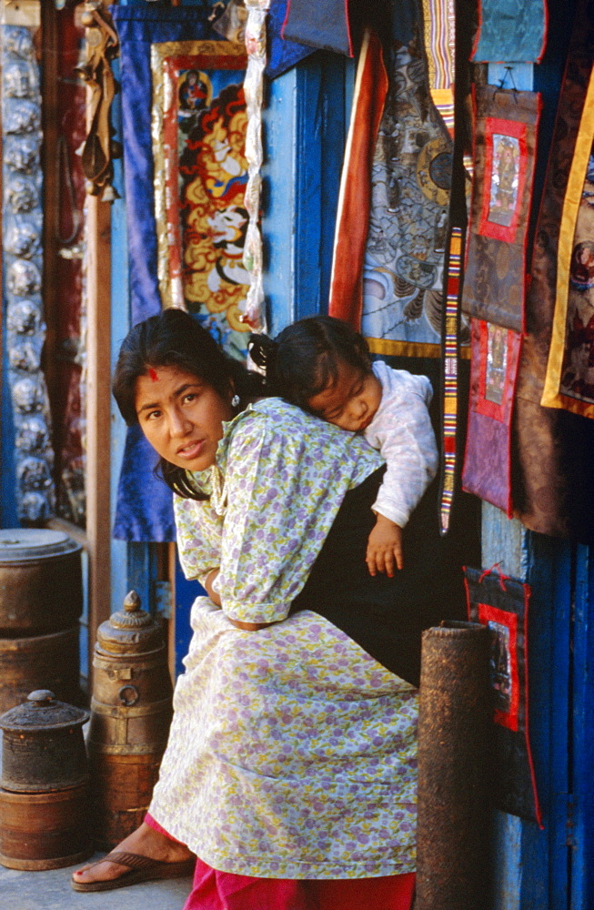 Woman and baby, cloth shopkeeper in temple square, Bodhnath, Kathmandu, Nepal