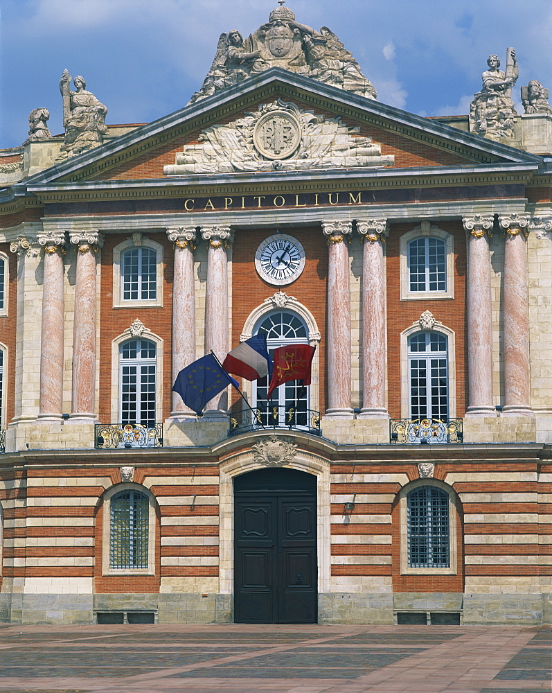 Flags flying below a clock on the Capitole building in Toulouse, Haute Garonne, Midi Pyrenees, France, Europe