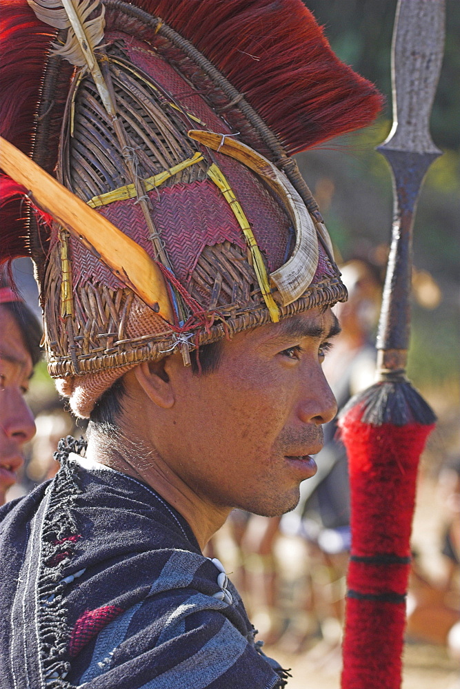 Naga man with spear wearing headdress made of woven cane decorated with wild boar teeth, Mithan horn (wild cow) red dyed goats hair and  hornbill feathers, Naga New Year Festival, Lahe village, Sagaing Division, Myanmar (Burma), Asia