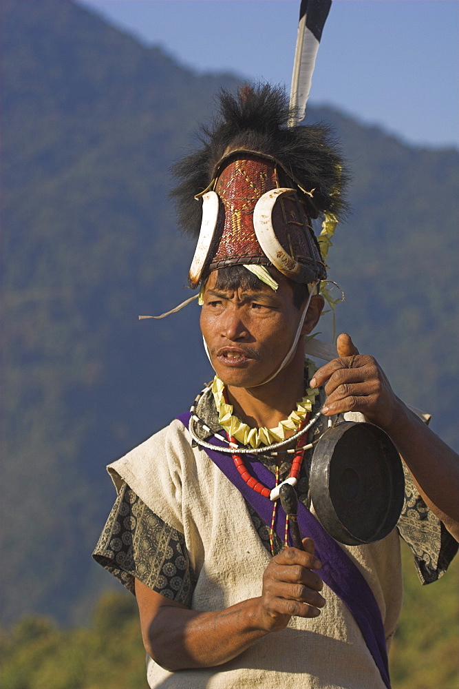 Naga man dancing and playing musical instrument, wearing headdress made of woven cane decorated with wild boar's teeth, bear fur and topped with hornbill feather, Naga New Year Festival, Lahe village, Sagaing Division, Myanmar (Burma), Asia