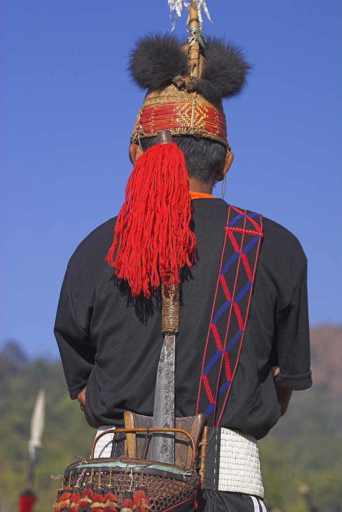 Naga men wearing headdress made of woven cane decorated with wild boar teeth, red dyed goats hair and  hornbill feathers, also wearing belt with dao holder also known as Dhama (a type of machete) Naga New Year Festival, Lahe village, Sagaing Division, Myanmar (Burma), Asia