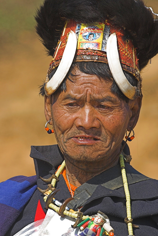 The Naga  (Macham tribe) chief of the village wearing traditional hat made of woven cane decorated with wild boars teeth and bear fur, also bead necklace with tiger teeth, Magyan Village, Sagaing Division, Myanmar (Burma), Asia