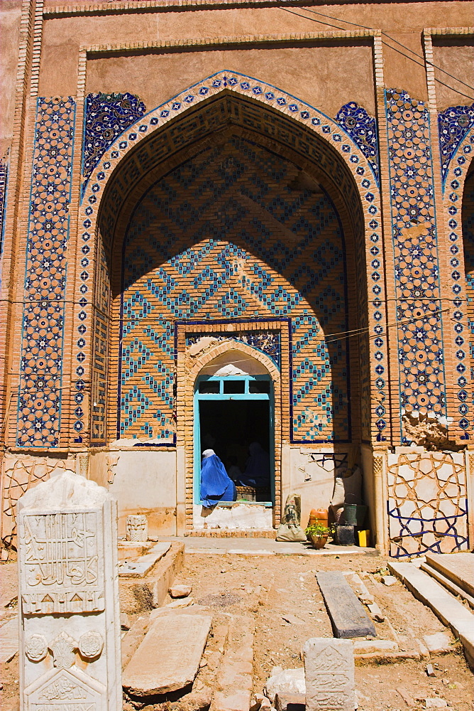 Lady pilgrim in blue burqa sitting in doorway at Sufi shrine of Gazargah, Herat, Herat Province, Afghanistan, Asia