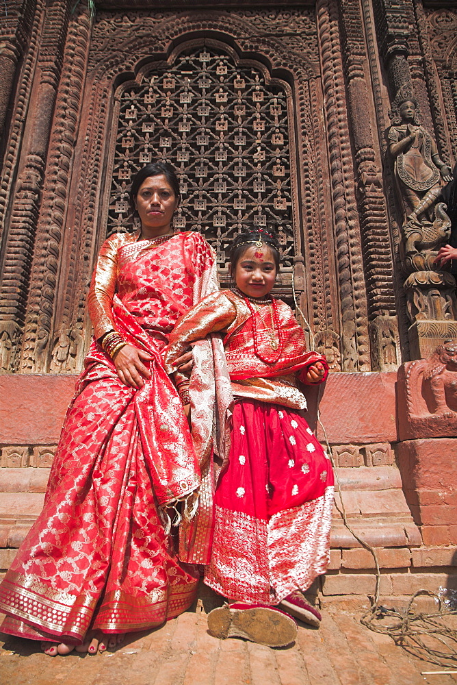 Mother and daughter stand in temple doorway at Kumari (living goddess) festival, Durbar Square, Kathmandu, Nepal, Asia