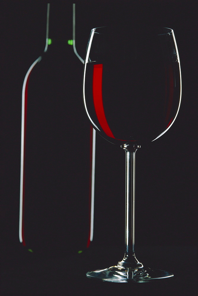 Studio shot of back-lit glass and bottle of red wine