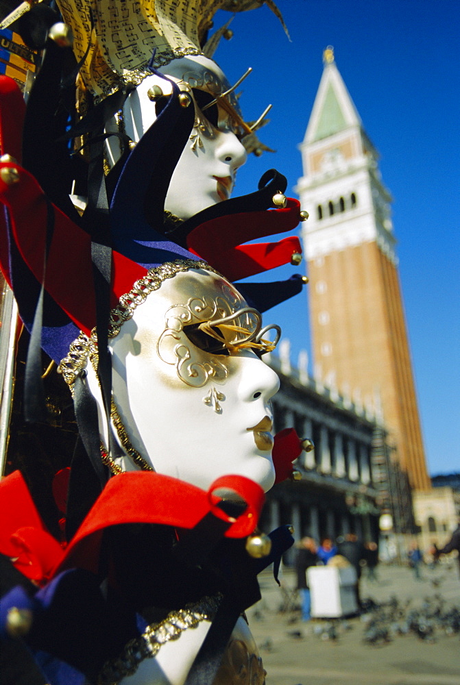 Carnival masks on souvenir stand and Campanile, St Marks Square, Venice, Veneto, Italy