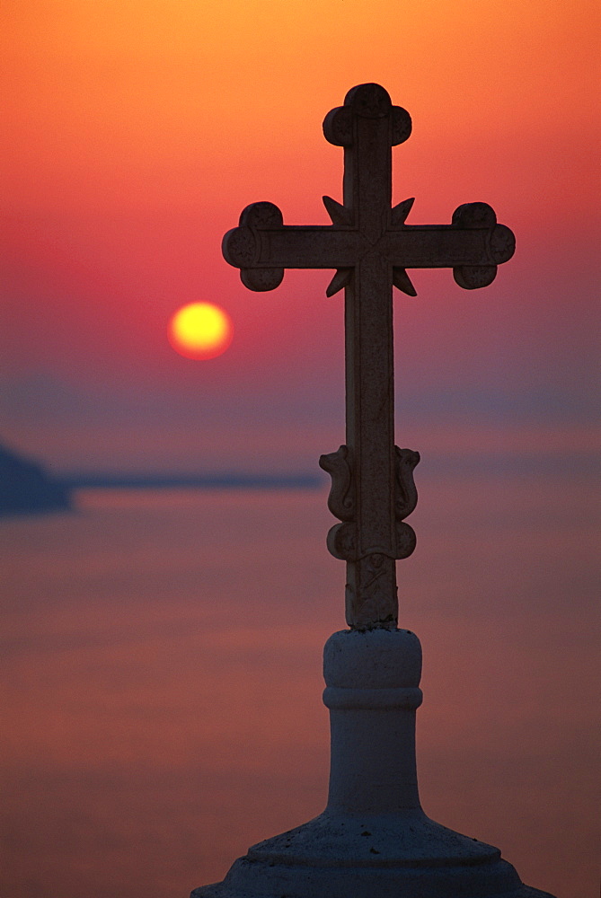 Cross on church dome with setting sun behind, Fira, Santorini, Cyclades, Greek Islands, Greece, Europe