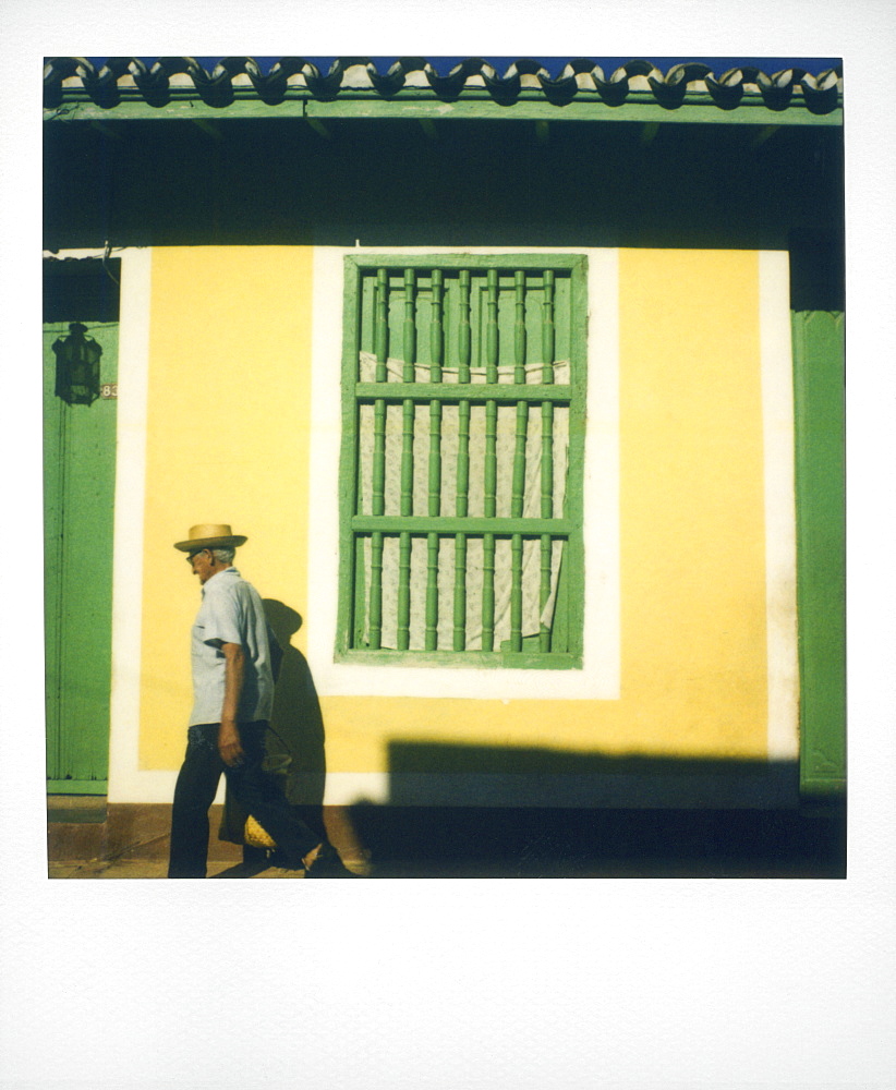 Polaroid of man walking past yellow wall with painted green window grille, Trinidad, Cuba, West Indies, Central America