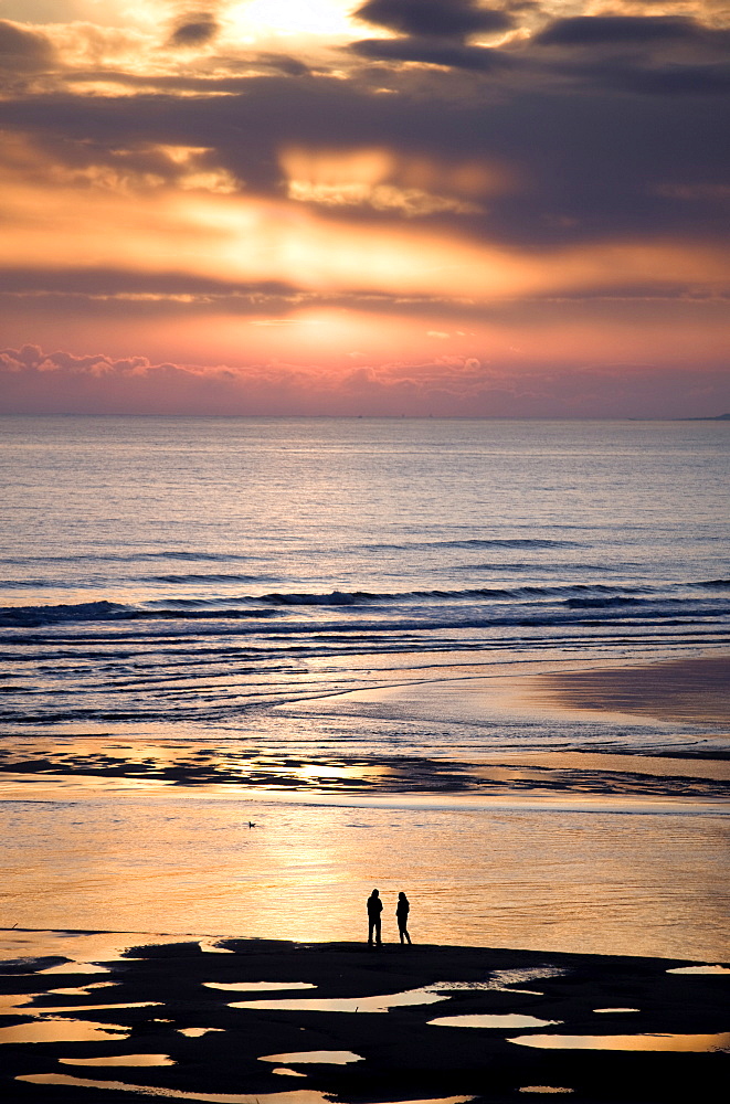 Man and woman in silhouette looking out over North Sea at sunsrise from Alnmouth Beach, near Alnwick, orthumberland, England, United Kingdom, Europe