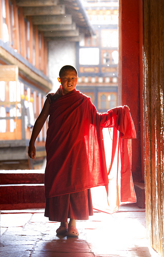 Young Buddhist monk in red robes backlit by evening sunlight at the Jakar Dzong, Jakar, Bumthang, Bhutan, Asia