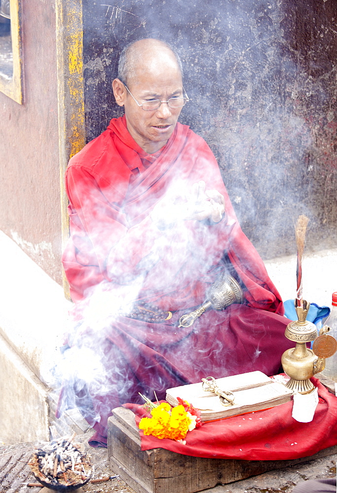 Buddhist monk near Swayambhunath offering to bless people at a roadside altar, Kathmandu, Nepal, Asia