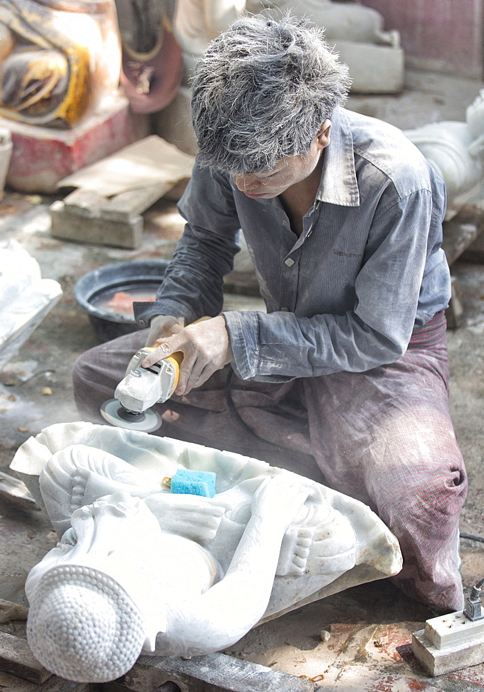 Local man carving a marble Buddha image using an angle grinder, and covered in white marble dust, stone carver's district, Amarapura, near Mandalay, Myanmar (Burma), Southeast Asia