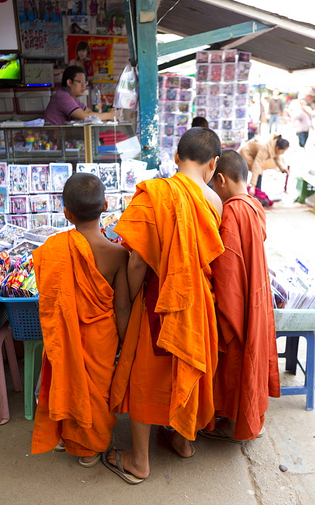 Three novice monks buying comics in the town market, Kengtung (Kyaingtong), Shan State, Myanmar (Burma), Asia