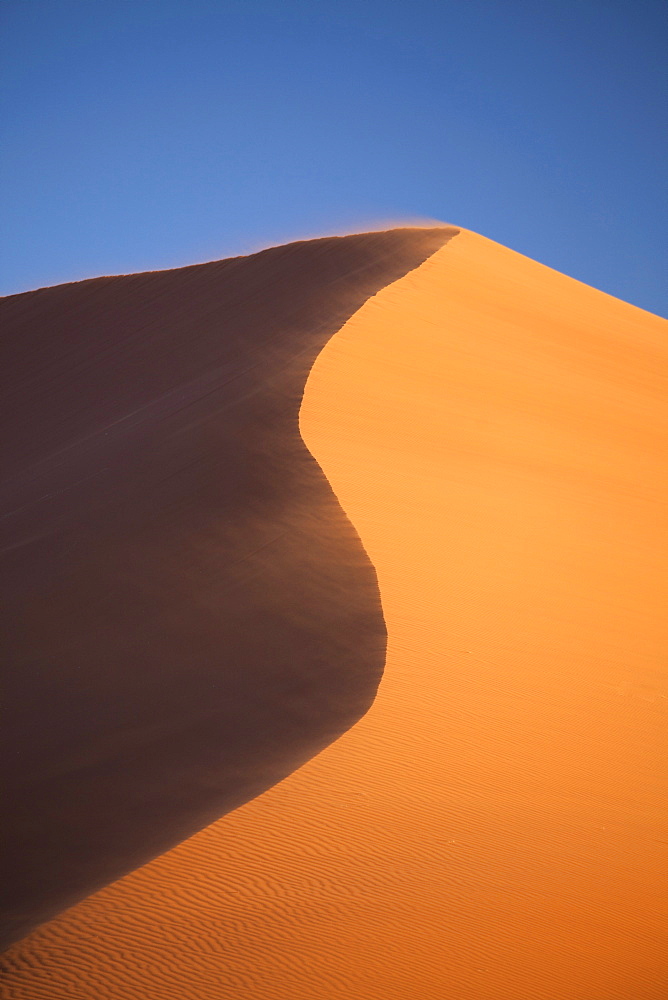 The orange sand and snaking ridge of Elim Dune against blue sky, Namib Desert near Sesriem, Namib Naukluft Park, Namibia, Africa